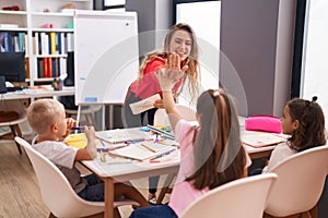 Teacher and group of kids having space lesson high five at classroom