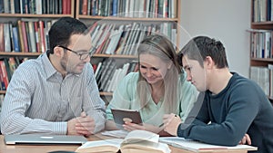 Teacher with group of students working on digital tablet in library