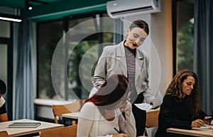 Teacher assisting students in modern classroom setting with natural light