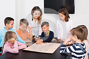 Teacher and happy kids thinking at table in classroom