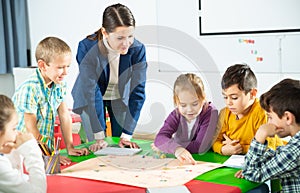 Teacher and happy schoolkids playing board game