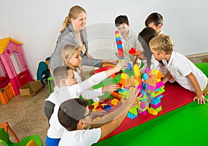 Teacher and happy schoolkids playing building blocks