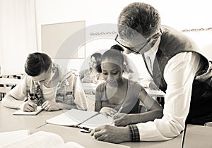 Teacher helping African-American schoolgirl in classroom