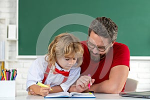 Teacher helping child student pupil from elementary school in classroom. Pupil kid student and teacher tutor in