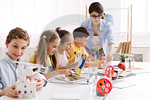 Teacher helping children with diy robots in class