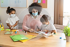 Teacher helping children in preschool during coronavirus outbreak - Back to school and covid-19 lifestyle - Focus on boy face