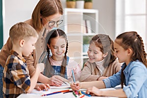 Teacher helping children with schoolwork at school photo