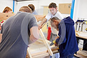 Teacher Helping College Students Studying Carpentry