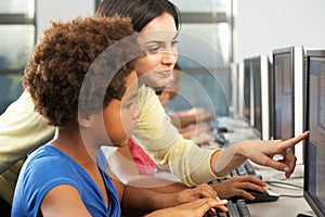 Teacher Helping Elementary Students Working At Computers