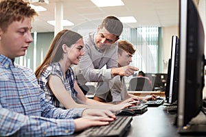 Teacher Helping Female High School Student Working In Computer C