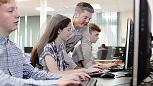 Teacher Helping Female High School Student Working In Computer Class