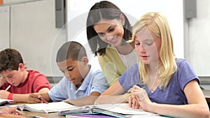 Teacher Helping Female Pupil In Class