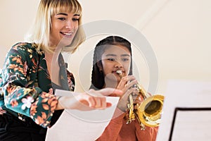 Teacher Helping Female Student To Play Trumpet In Music Lesson