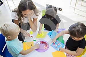 Teacher helping her pupils folding origamis