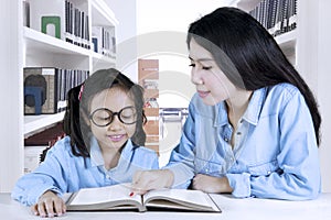 Teacher helping her student to reading a book