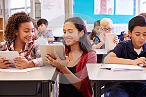 Teacher helping kids with computers in elementary school