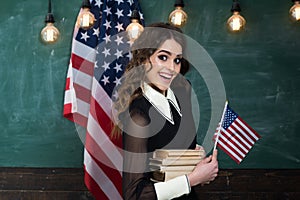 Teacher helping kids with computers in elementary school on the USA national flag background. Teacher conveys sense of