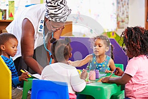 Teacher helping kids in a preschool class photo