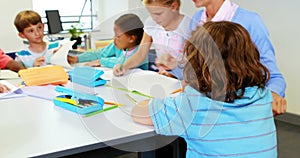 Teacher helping kids with their homework in classroom