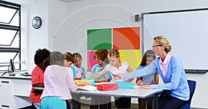 Teacher helping kids with their homework in classroom