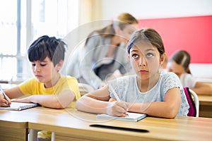 Teacher helping kids to complete exercises