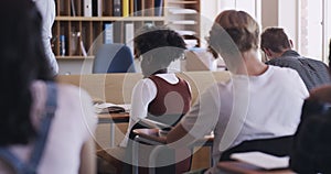 Teacher helping a learning student asking a question by raising her hand, in classroom at her desk. Education, study and