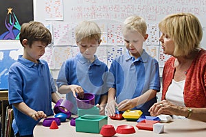 Teacher Helping Little Boys Assemble Educational Puzzle Toys