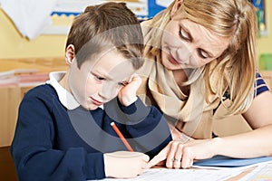 Teacher Helping Male Elementary School Pupil With Problem