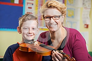 Teacher Helping Male Pupil To Play Violin In Music Lesson