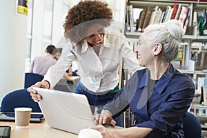 Teacher Helping Mature Student With Studies In Library