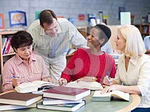 Teacher helping mature students in library