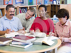 Teacher helping mature students in library