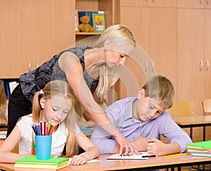 Teacher helping pupil explains how to solve the task photo
