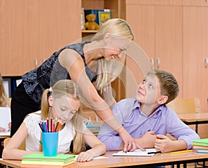Teacher helping pupil explains how to solve the task photo