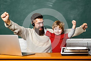 Teacher helping pupils studying on desks in classroom. Preschool pupil. Young or adult. Teacher and kid. Chalkboard copy