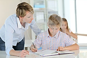 Teacher helping schoolboy in class