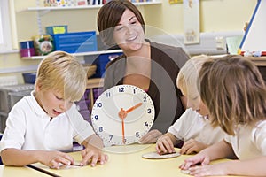 Teacher helping schoolchildren learn to tell time photo