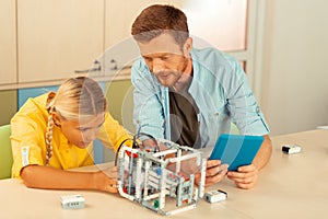 Teacher helping a schoolgirl building a robot.