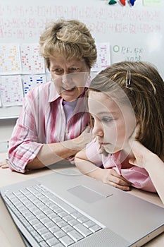 Teacher Helping Schoolgirl Use Laptop