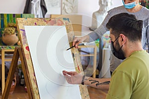 Teacher helping student in art scholl, student with protective mask drawing picture photo