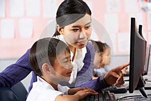 Teacher Helping Student During Computer Class