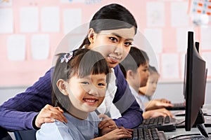 Teacher Helping Student During Computer Class