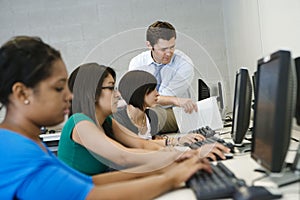 Teacher Helping Students In Computer Lab