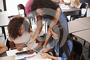 Teacher helping students with technology, high angle