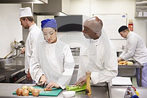 Teacher Helping Students Training To Work In Catering