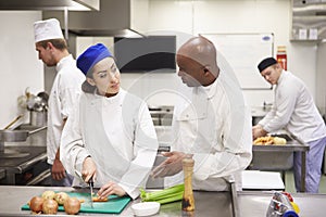 Teacher Helping Students Training To Work In Catering