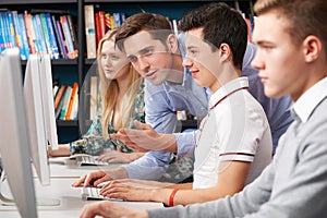 Teacher Helping Students Working At Computers
