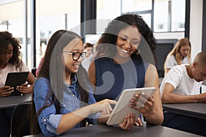 Teacher helping teenage schoolgirl with tablet computer