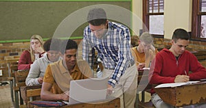 Teacher helping a teenager in high school class