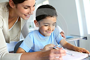 Teacher helping young boy wiritng